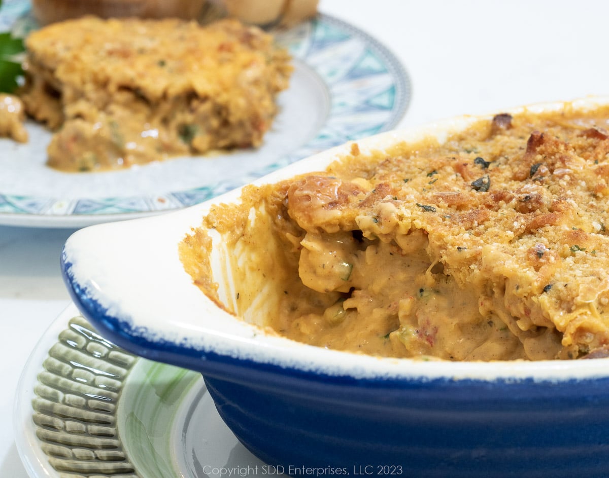 Crawfish au gratin in a baking dish with a serving on a plate