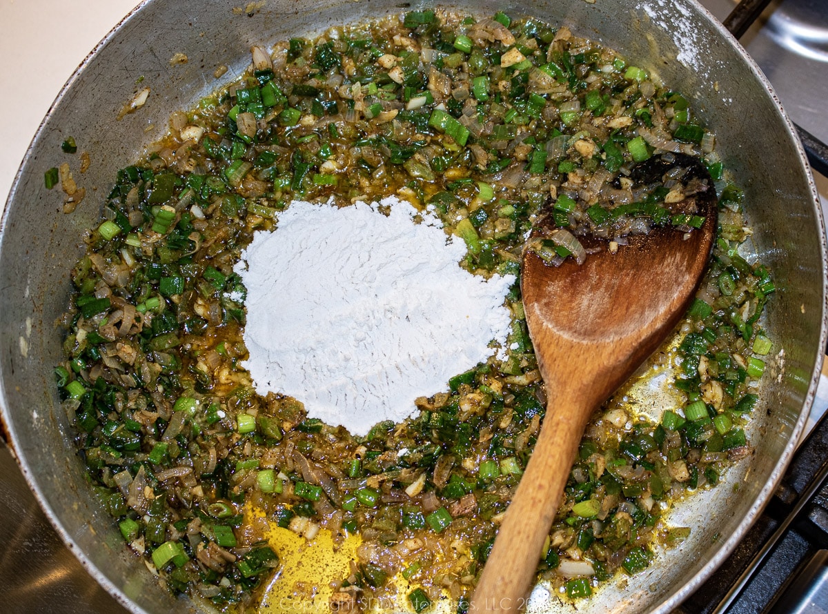 flour added to vegetables in a frying pan