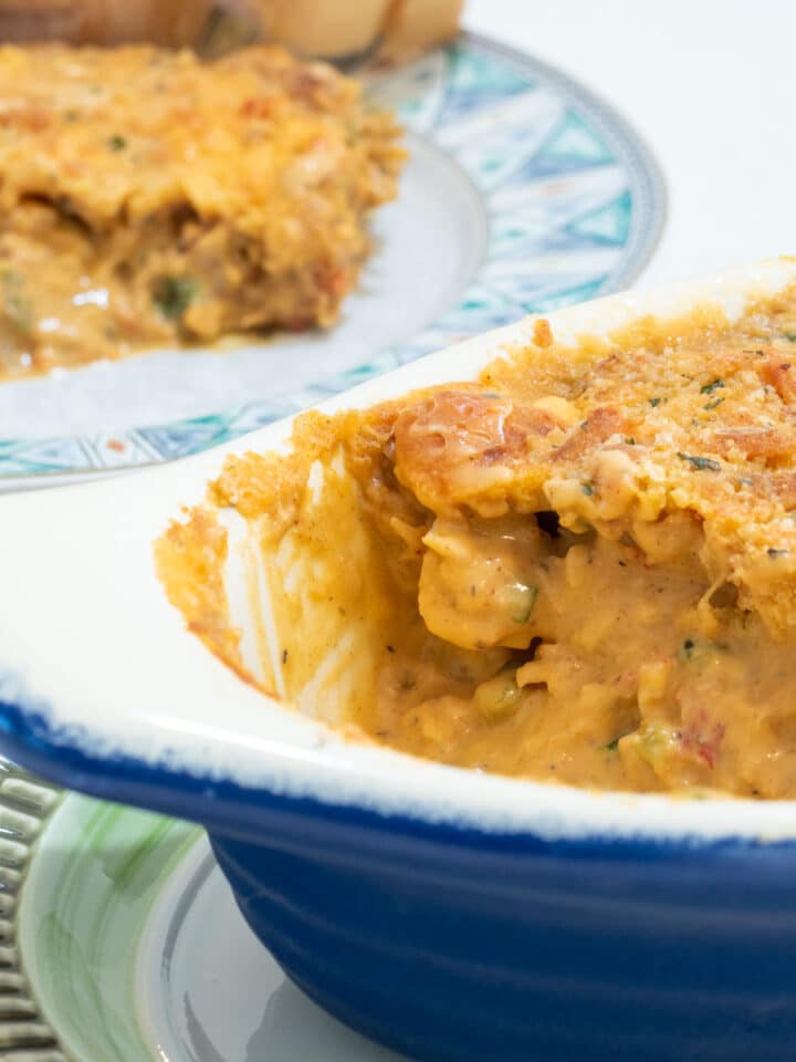 crawfish au gratin in a gratin dish with a serving plate in the background