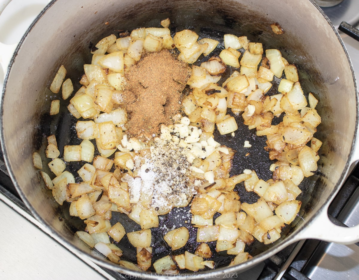 herbs and spices added to frying vegetables in a Dutch oven