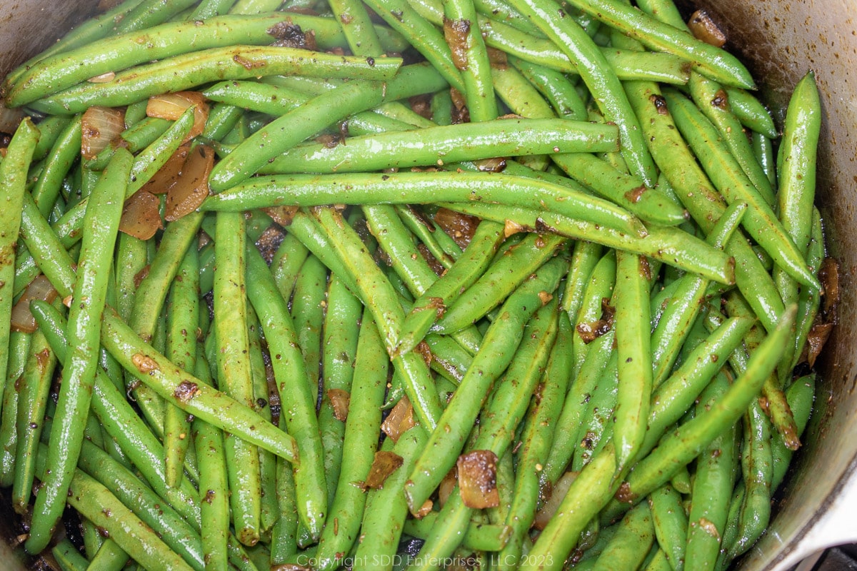 fresh green beans added to seasonings in a Dutch oven