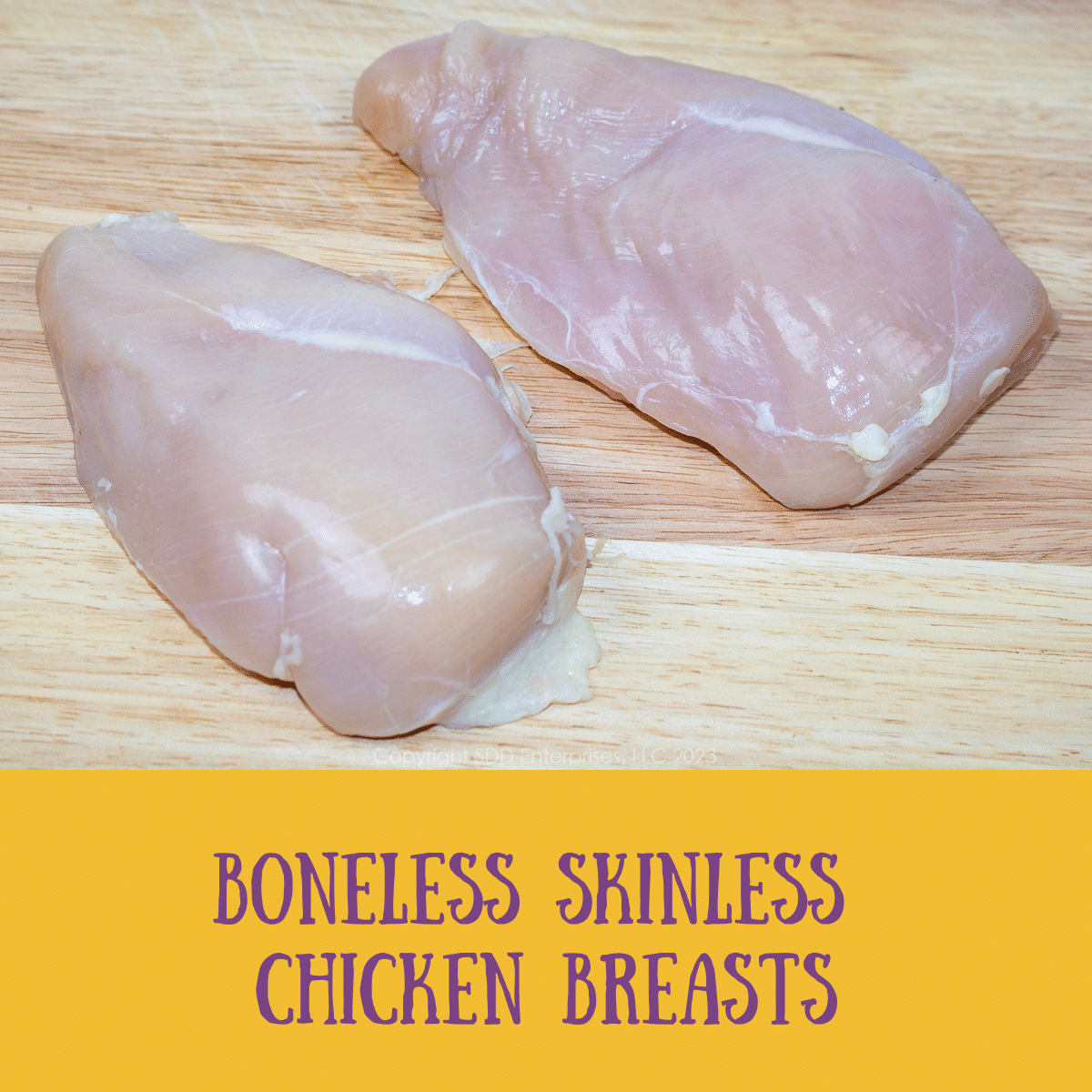 two boneless skinless chicken breasts on a cutting board.