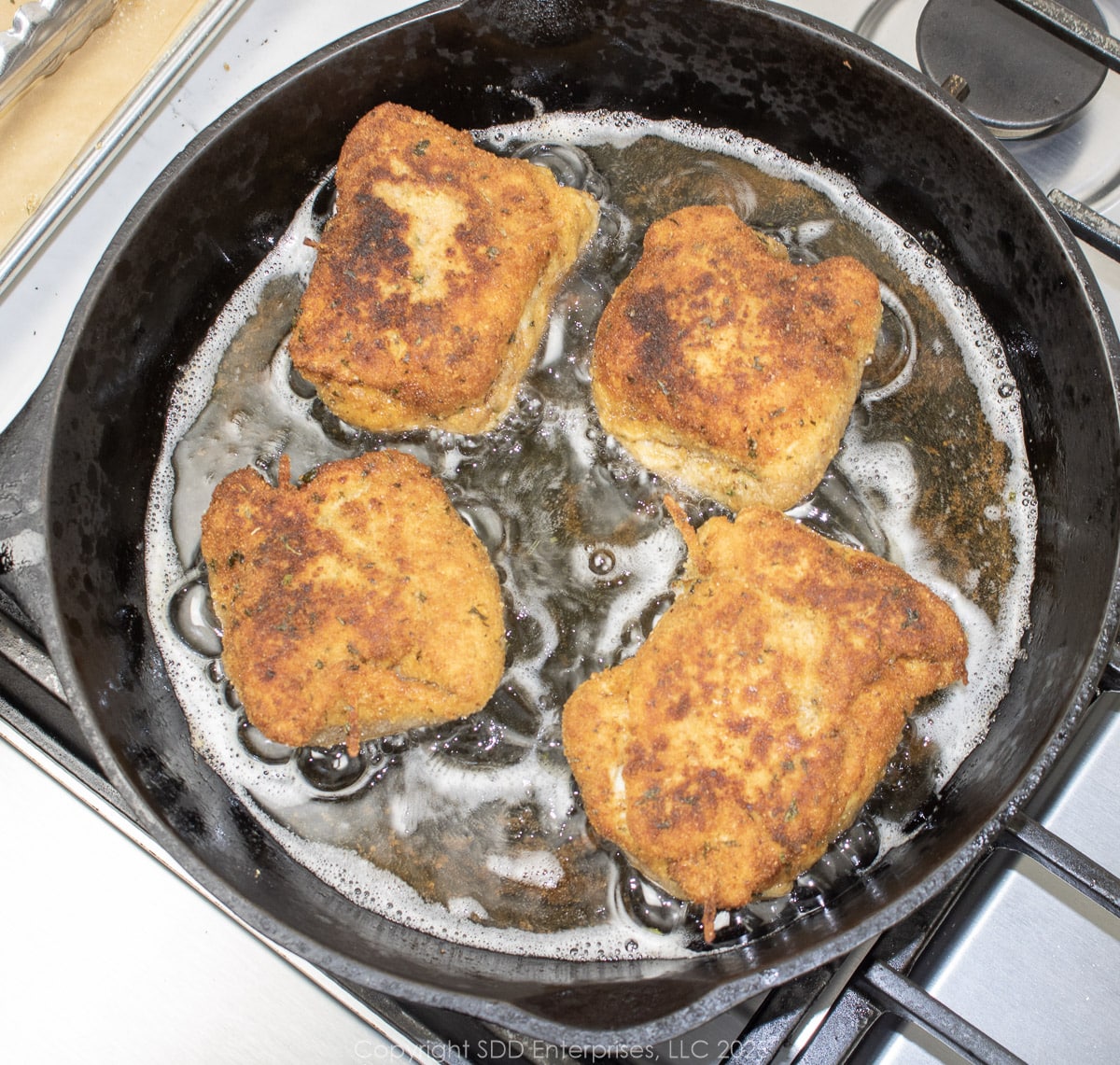 cajun chicken kievs frying in a skillet