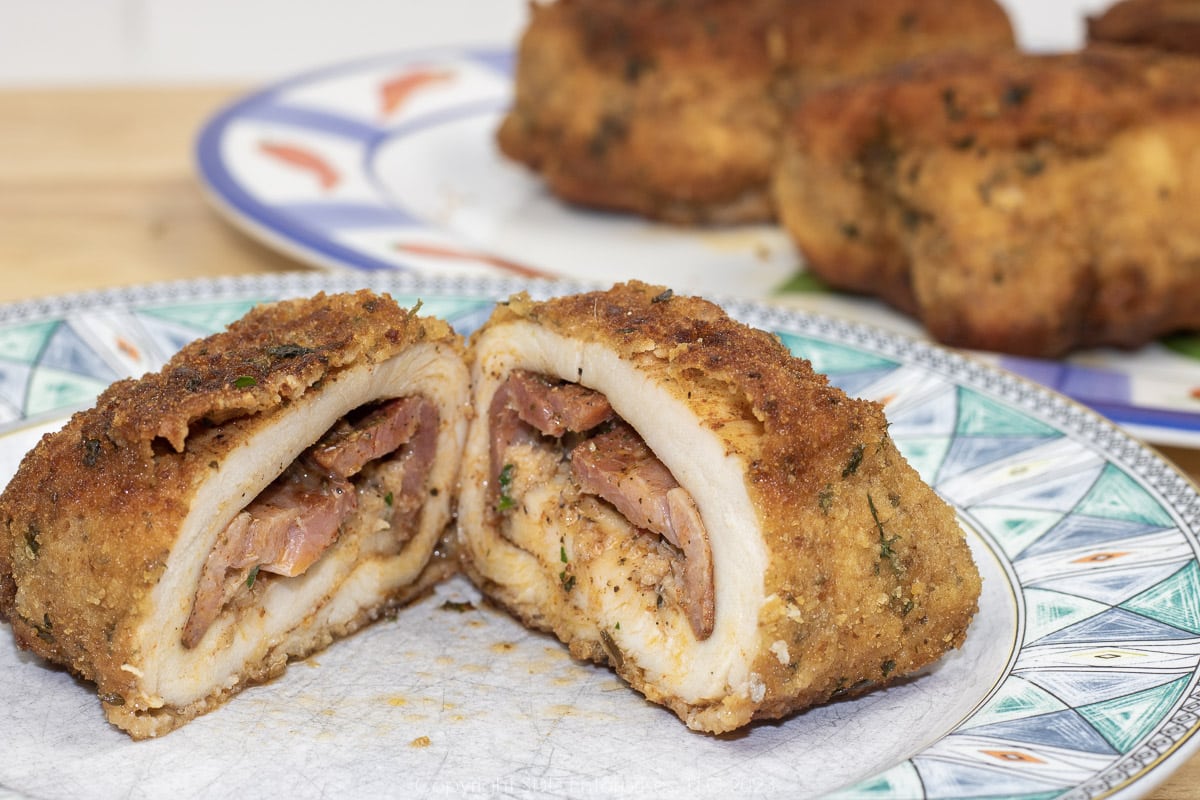 Baked chicken kiev sliced in two on a green and white plate