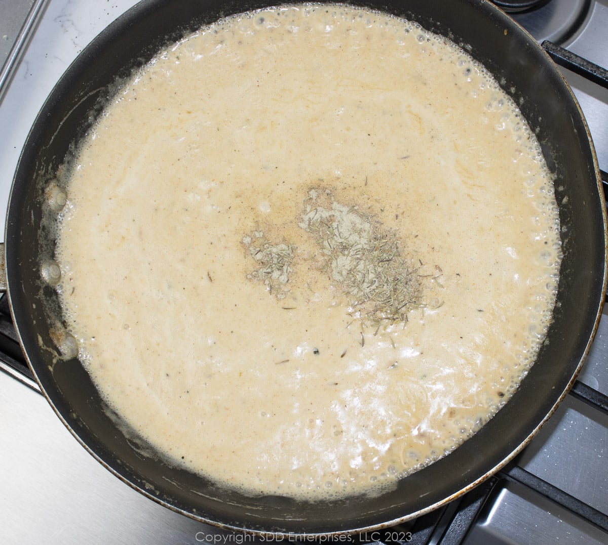 Seasoning a cream sauce with pepper and thyme