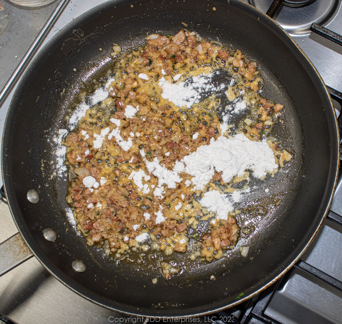 AP flour added to compound butter, shallots and andouille in a saute pan