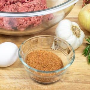 cajun seasoning in a small prep owl with other ingredients on a cutting board