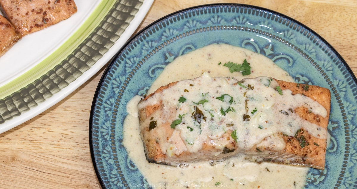 baked salmon on a blue green plate with cilantro creole mustard cream sauce