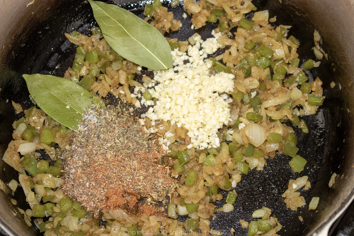 garlic and spices added to fried onions and peppers in a Dutch oven