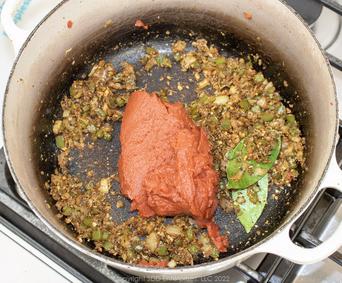 tomato paste added to fried onions and peppers in a Dutch oven