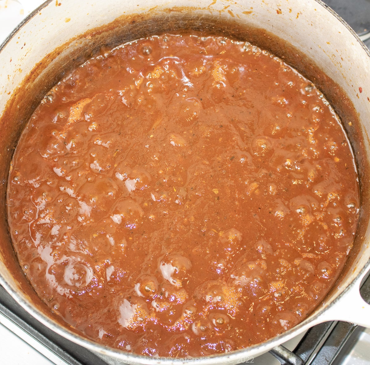 Red gravy simmering in a Dutch oven