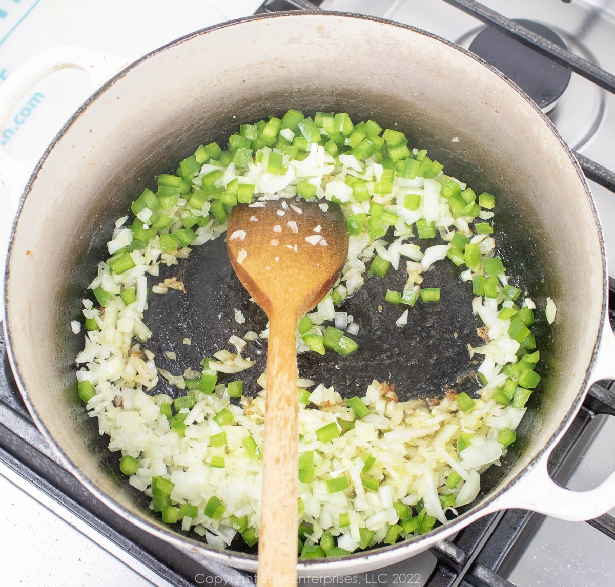 yellow onions and bell peppers frying in a Dutch oven