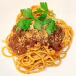 red Italian gravy ladled over spaghetti with parsley garnish