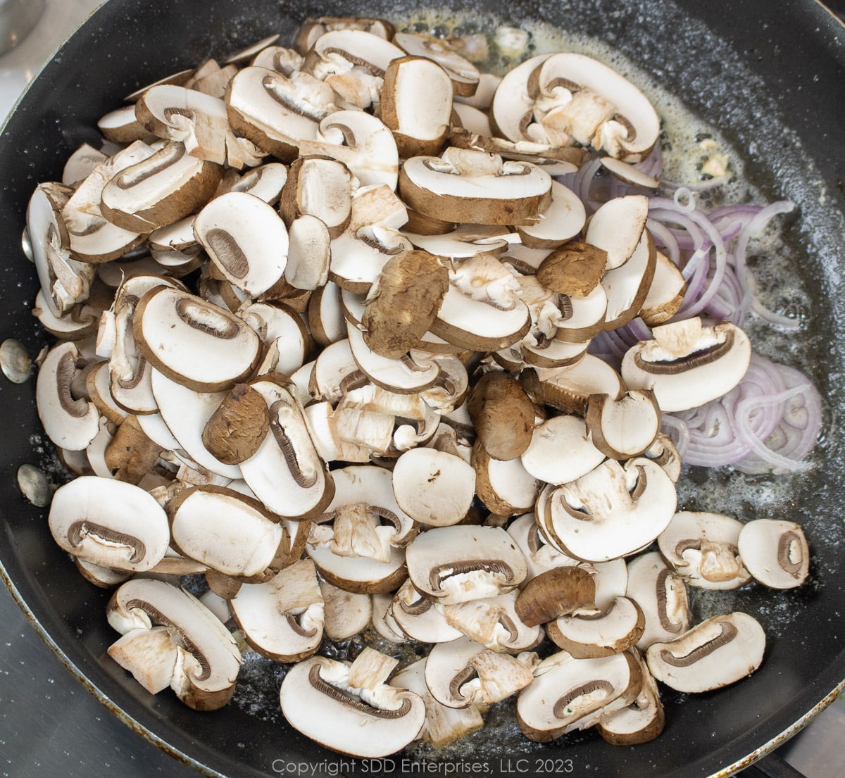 sliced mushrooms and shallots in a frying pan