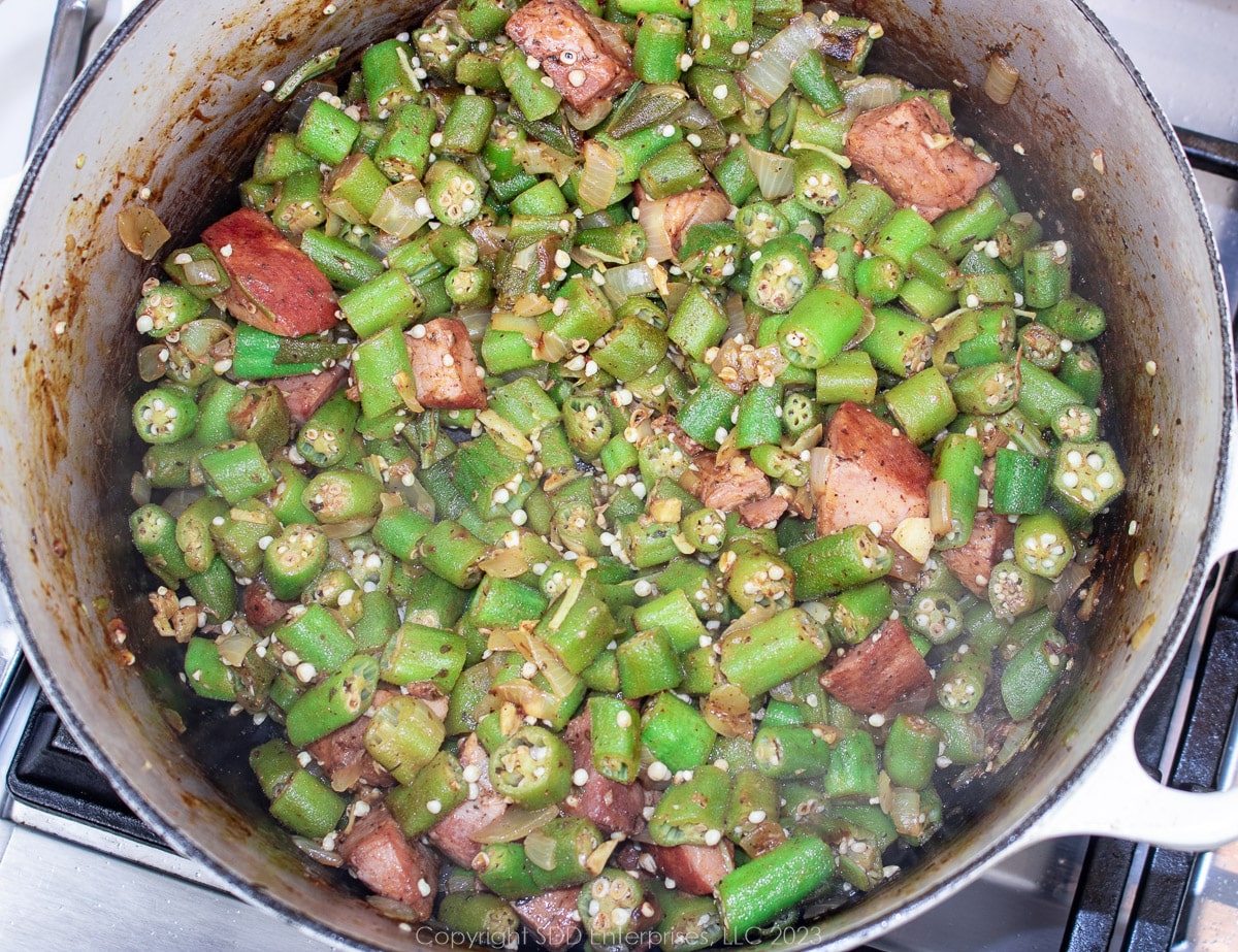 smothering chopped okra with onions, seasonings and ham in a Dutch oven