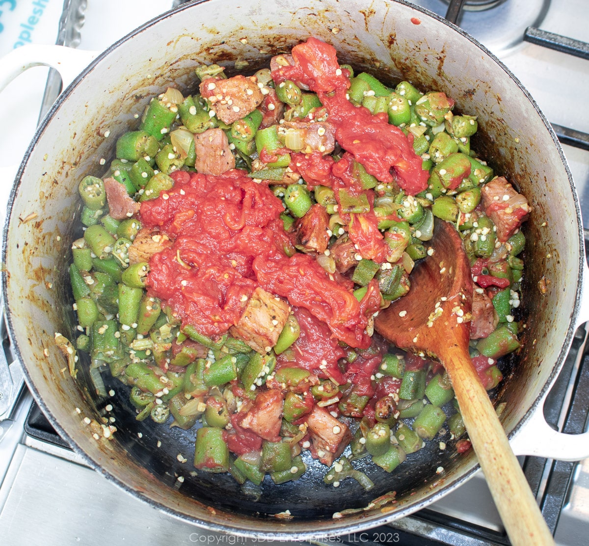 tomatoes added to smothering okra in a Dutch oven