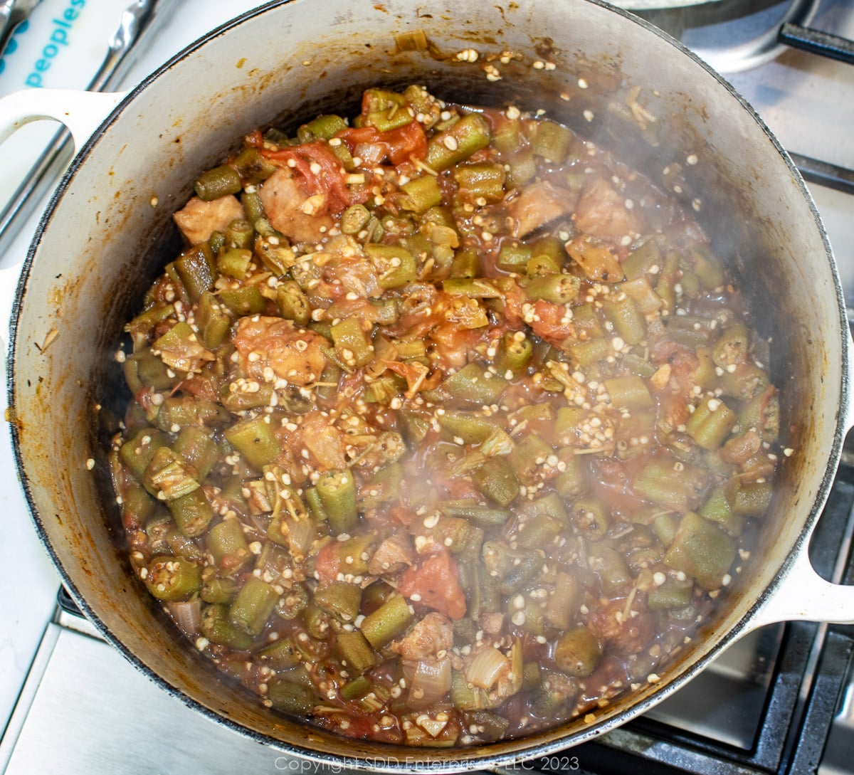 okra, tomatoes, onions and ham smothering in a Dutch oven