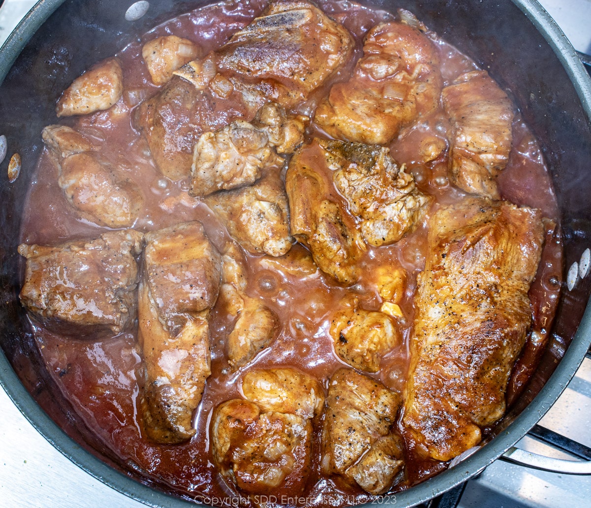 country style spareribs added to braising liquid in a Dutch oven