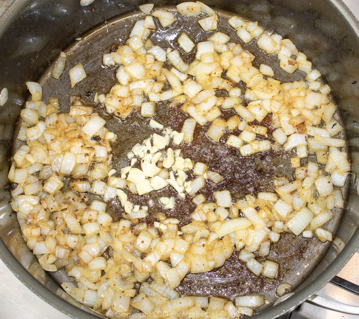 chopped garlic and onions cooking in a Dutch oven