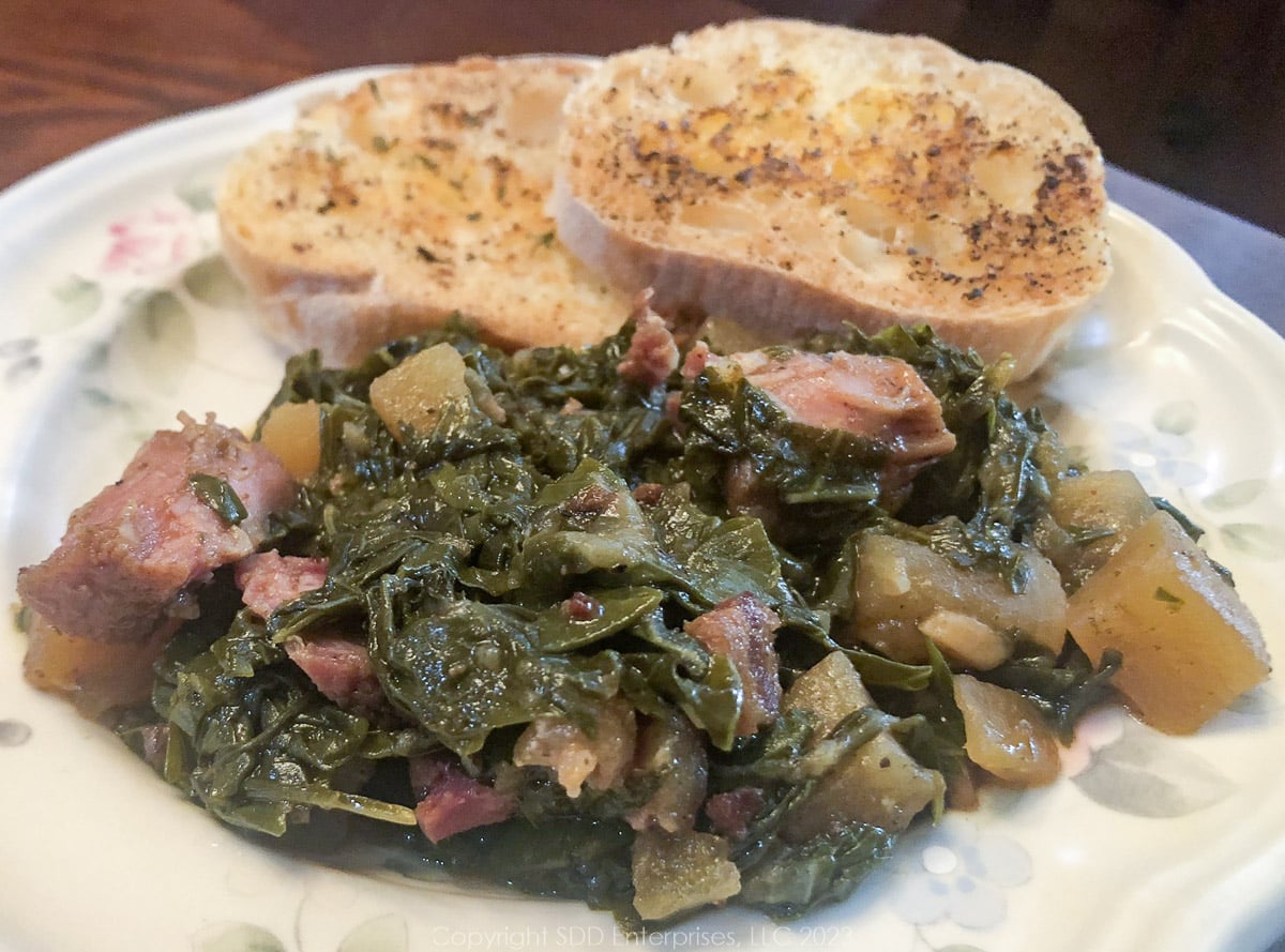 smothered turnip greens with garlic bread on a white plate