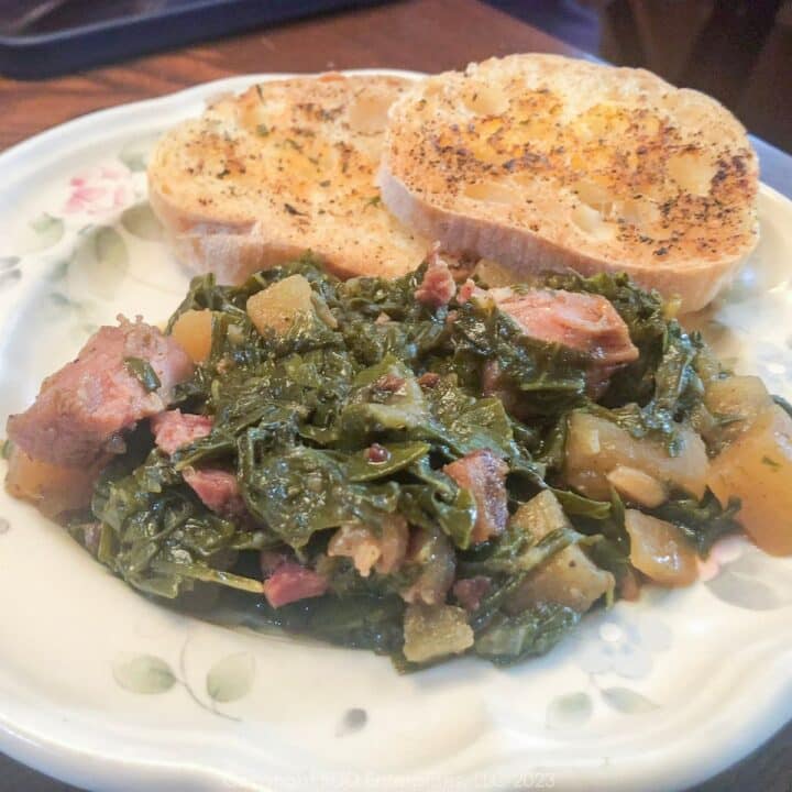 Smothered Turnip Greens on a white plate with garlic bread