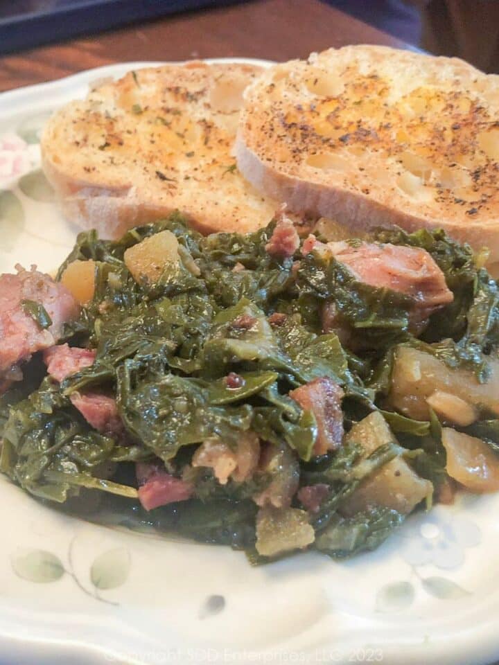 Smothered Turnip Greens on a white plate with garlic bread