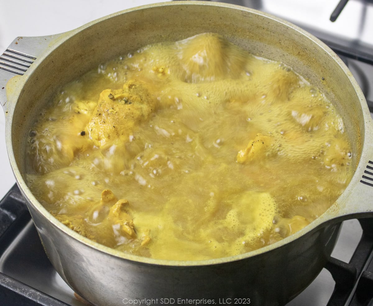 Seasoned chicken breasts boiling in a Dutch oven