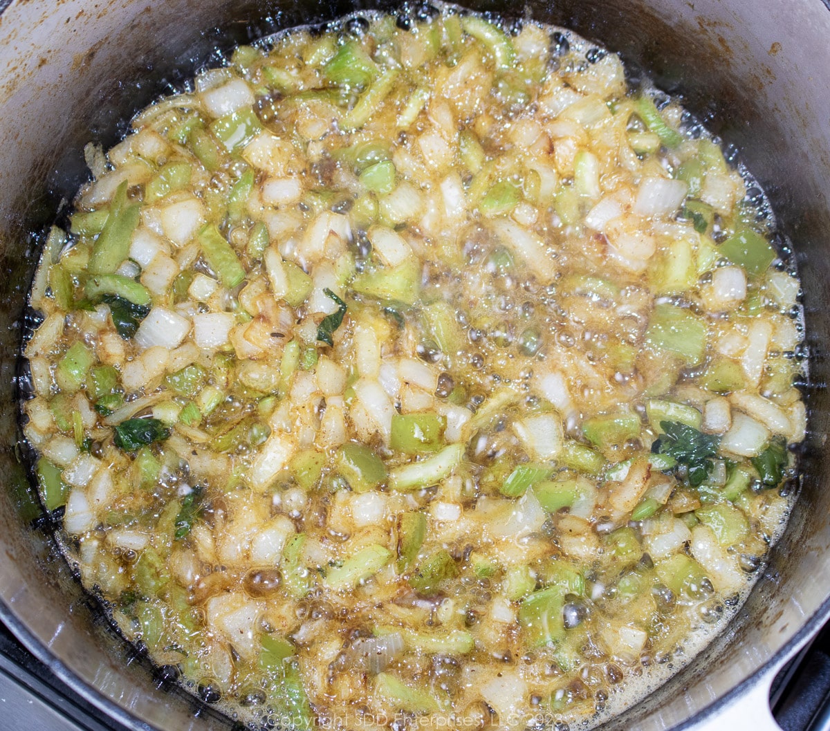 bell peppers, celery and onions sautéing in butter in a Dutch oven