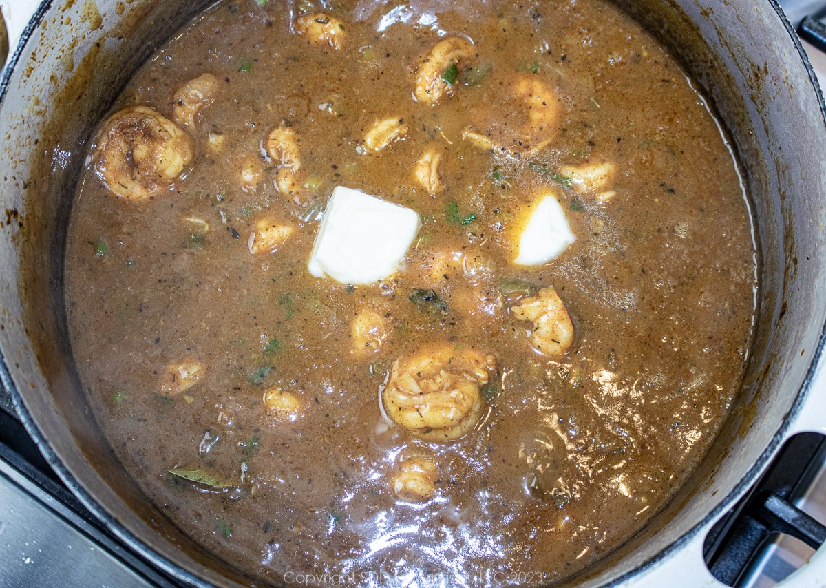 finishing étouffée with butter in a Dutch oven