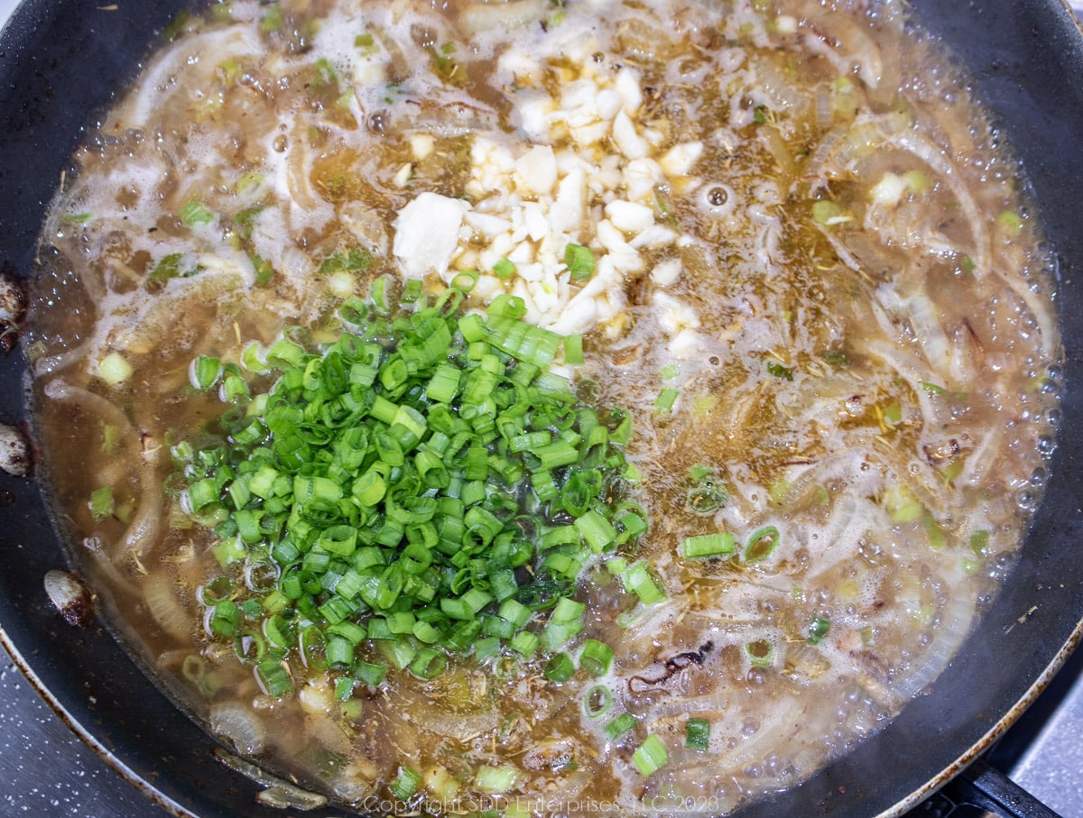 aromatics added to a simmering wine sauce in a saute pan