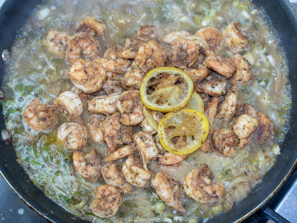 seared shrimp and lemon slices in sauce  in a saute pan