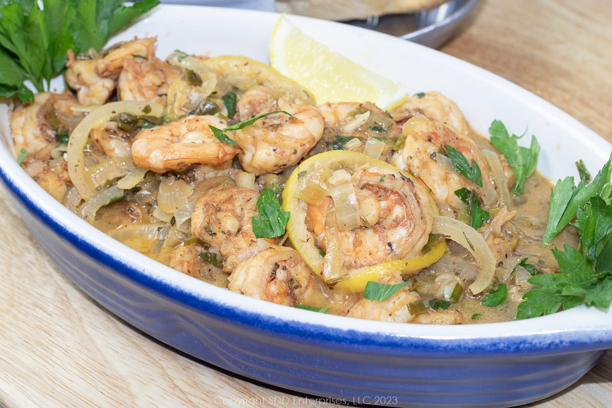 shrimp in white wine sauce in a serving bowl with garnish