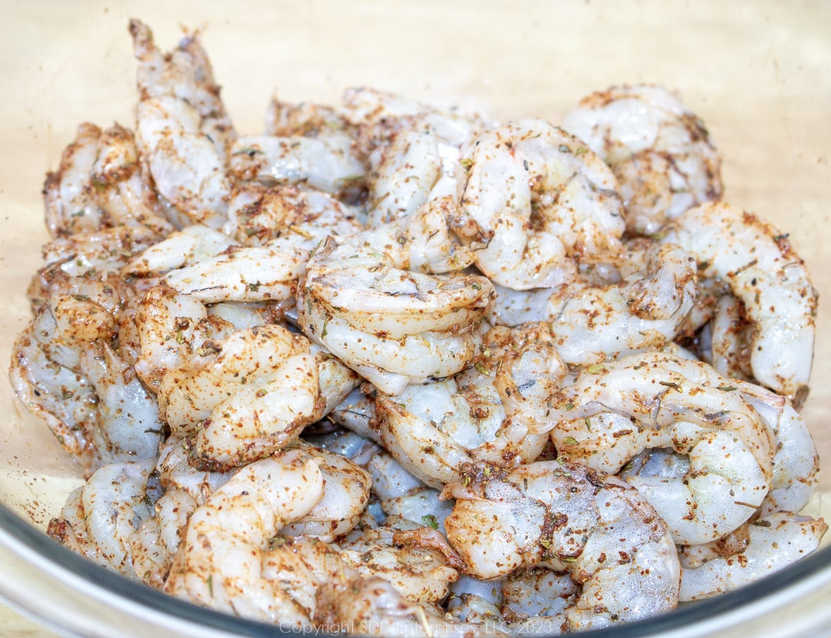 peeled and deveined shrimp with seasoning in a glass bowl