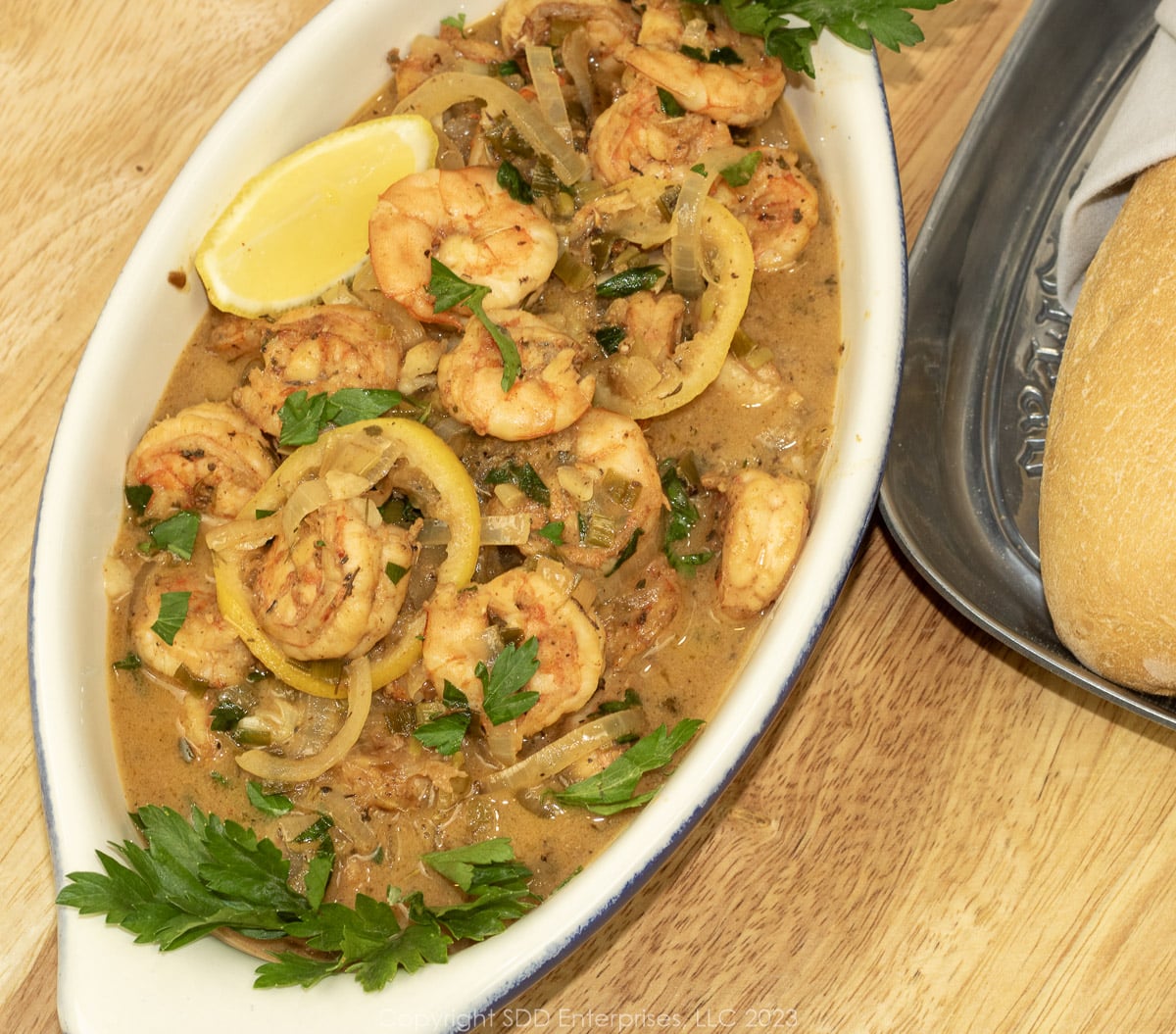 Shrimp in White Wine Sauce in a serving bowl with garnish and French bread