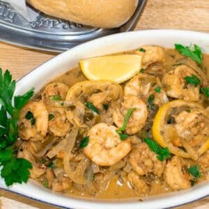 shrimp in white wine sauce in a serving bowl with french bread and garnish