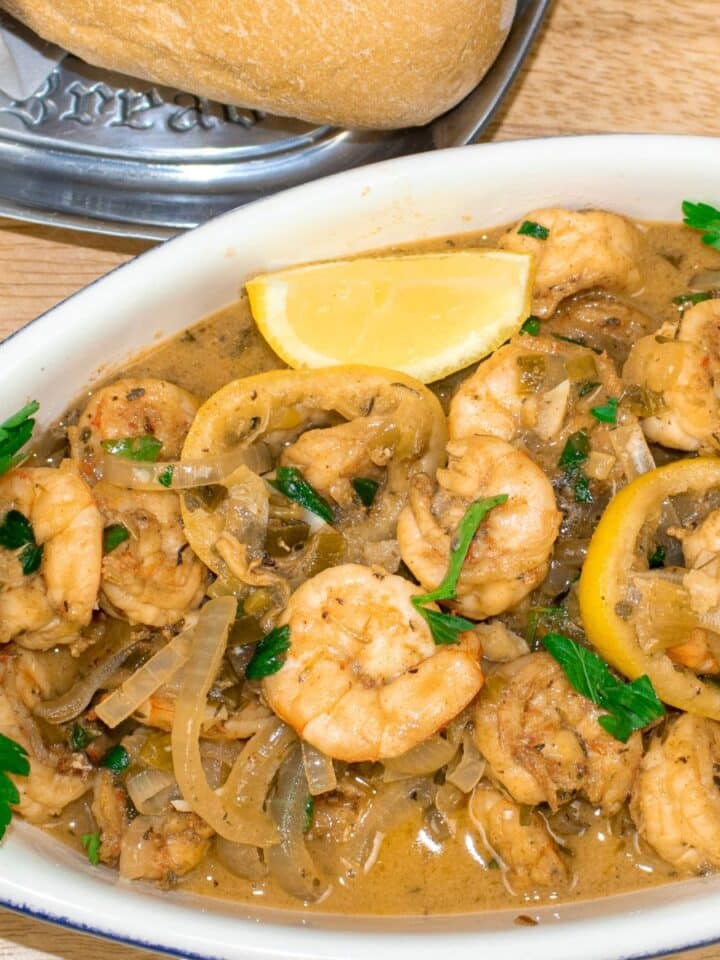 shrimp in white wine sauce in a serving bowl with french bread and garnish