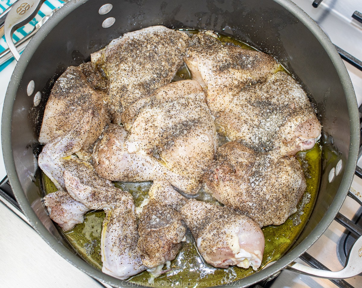 cut chicken, coated in olive oil and seasoned with salt and pepper in a Dutch oven.