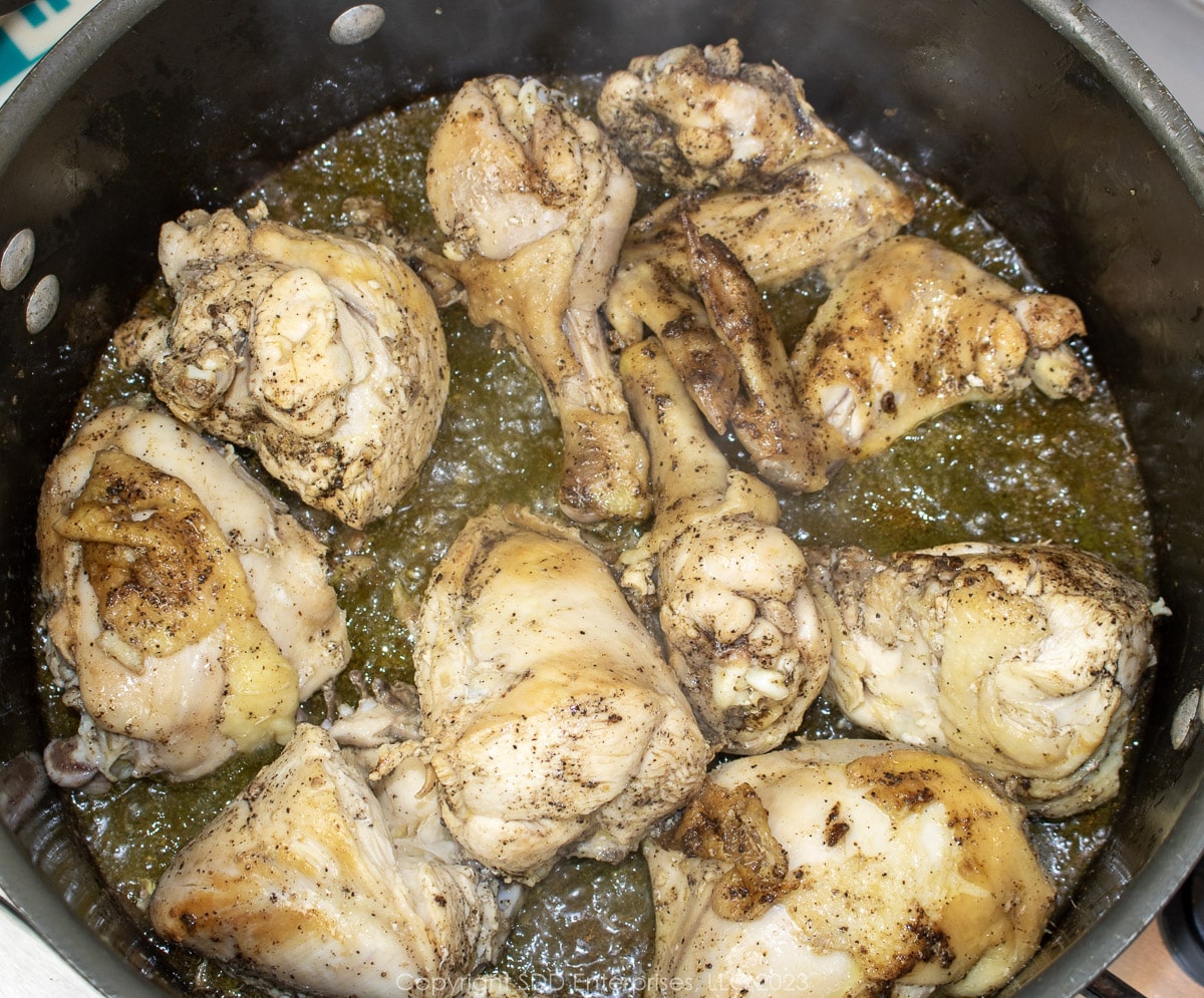 Chicken pieces being browned on all sides in a Dutch oven.