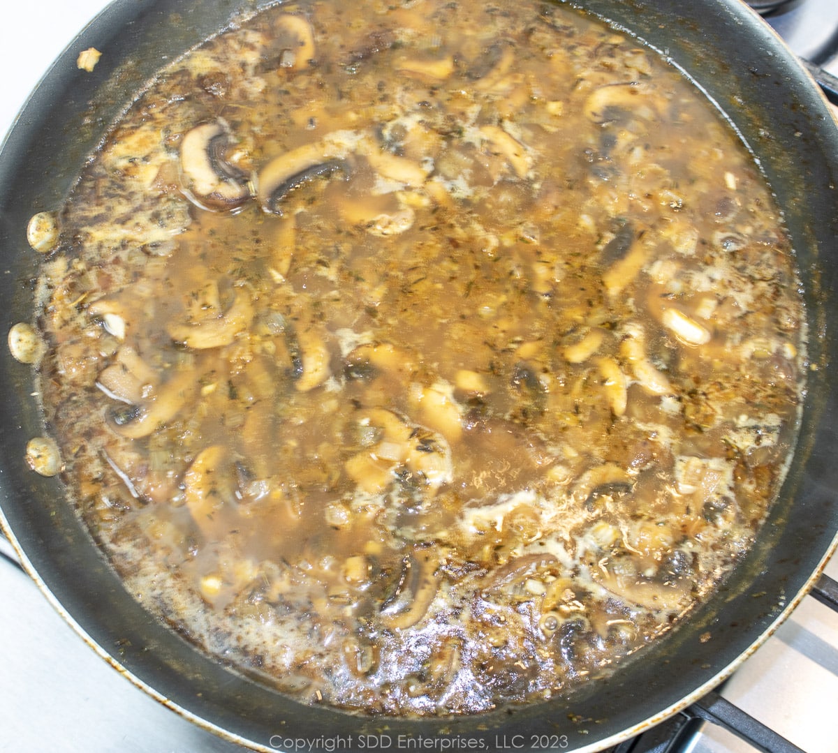 chicken stock simmering with vegetables in a skillet