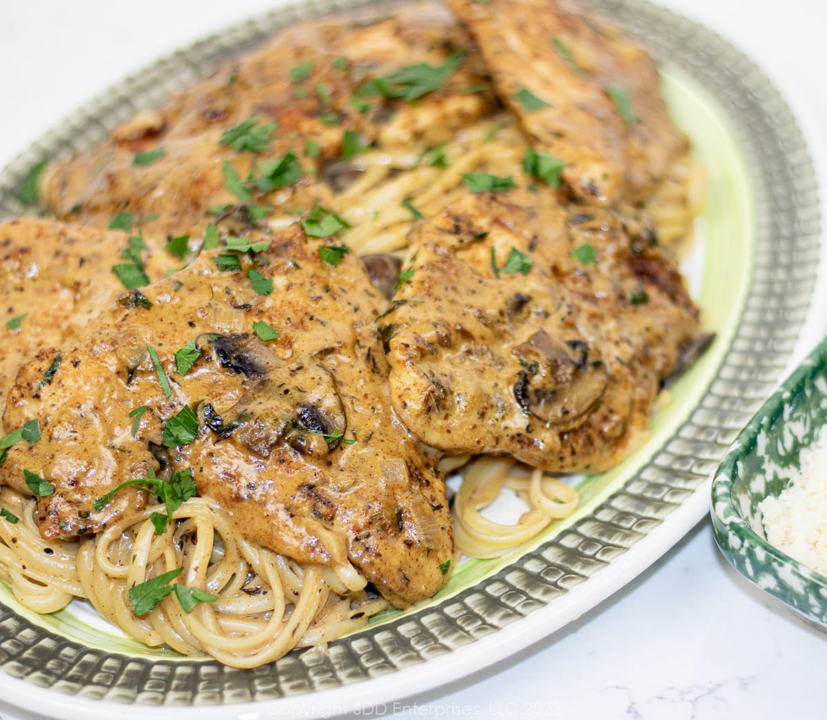 Chicken with Creamy Mushroom Sauce over pasta on a serving platter.