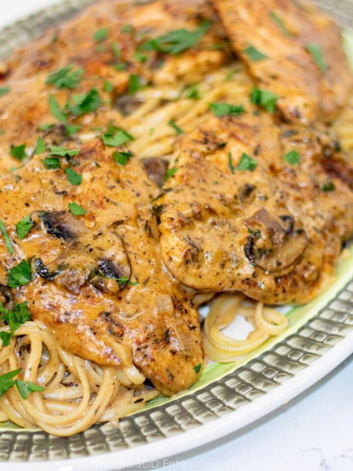Chicken with Creamy Mushroom Sauce over pasta on a serving platter