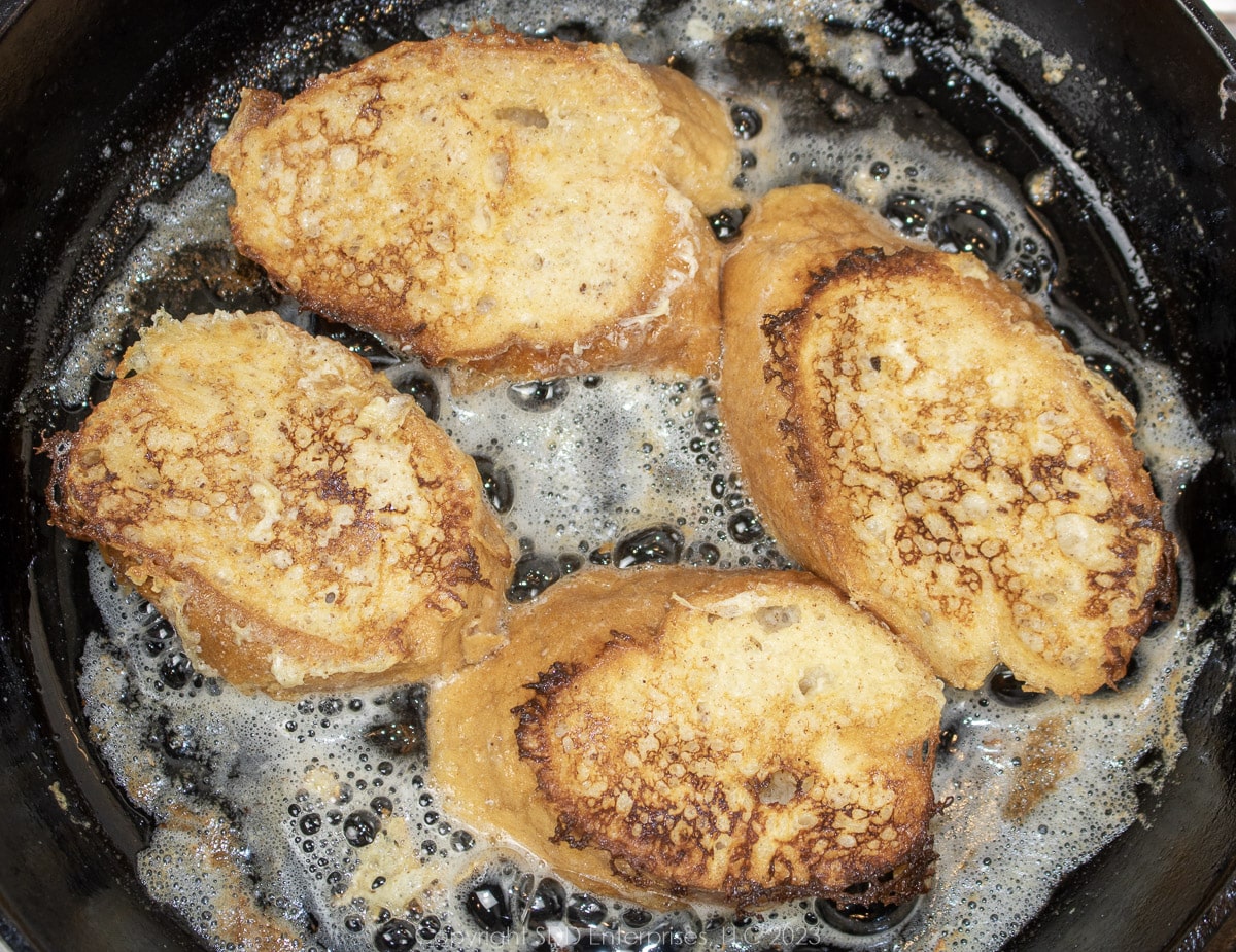 Soaked French bread frying in butter in a cast iron skillet.