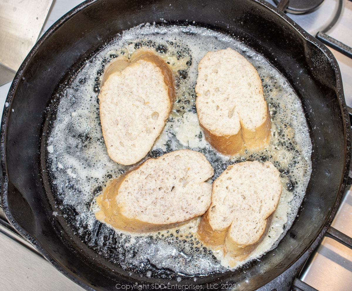 Soaked French bread frying in butter in a cast iron skillet.