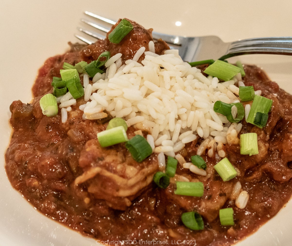 Shrimp Creole with rice and garnish in a white bowl with a fork.