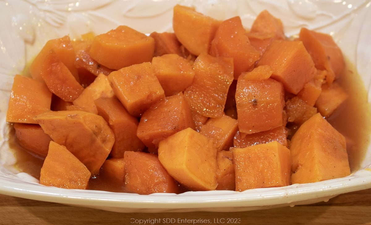 candied sweet potatoes in a white serving bowl.