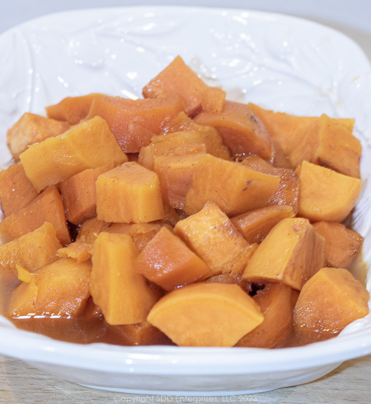 candied sweet potatoes in a white serving bowl.