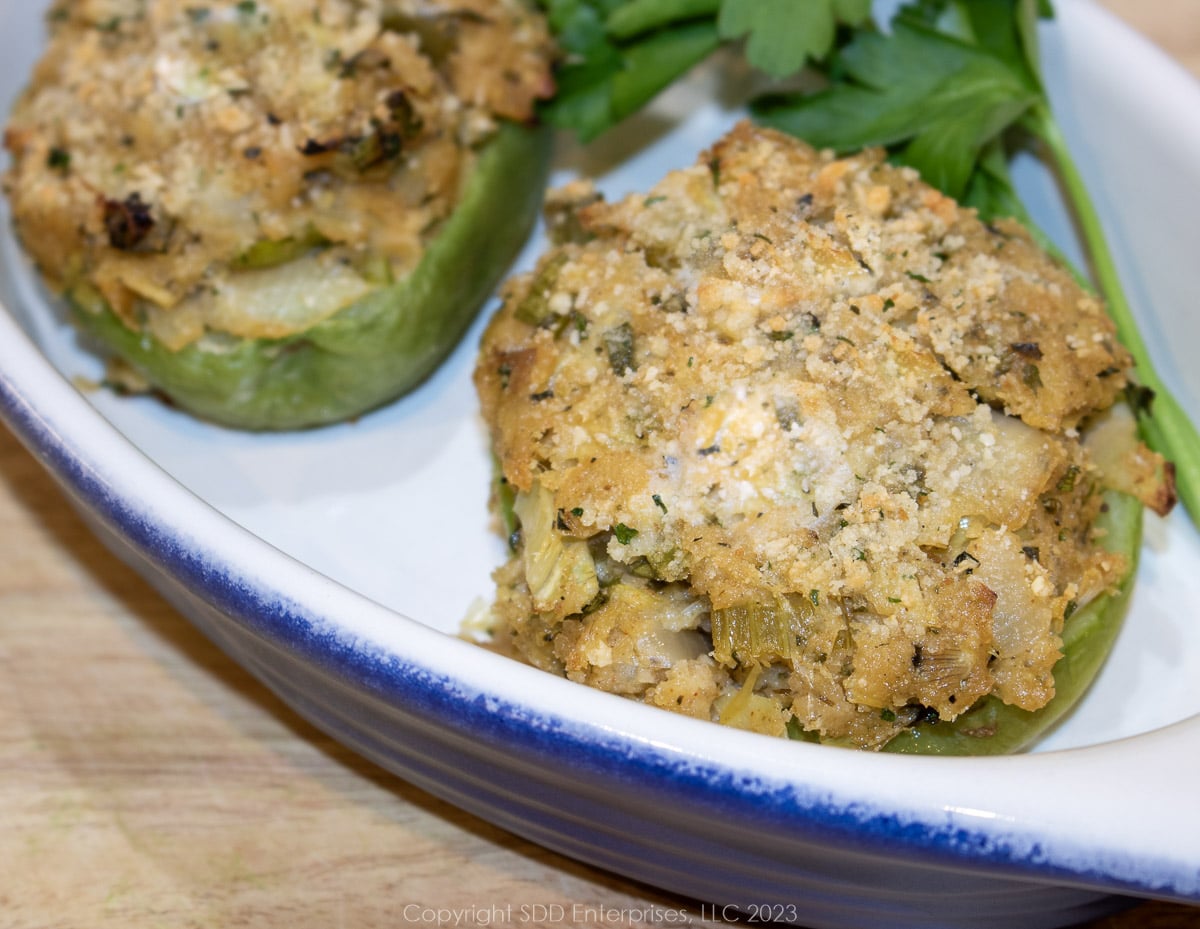 Two stuffed mirlitons in a blue and white serving dish with garnish.