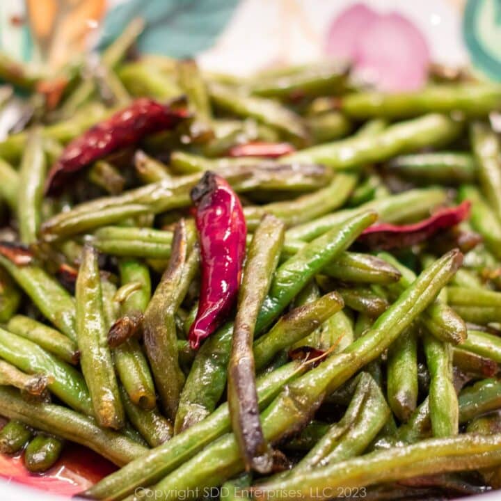 Sautéed green beans with a chili pepper in a serving bowl.