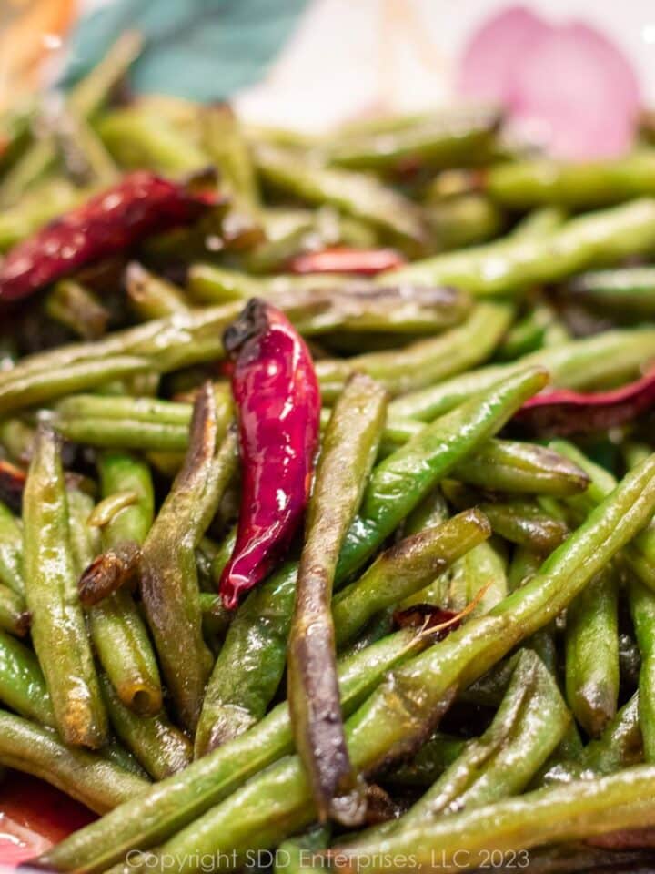 Sautéed green beans with a chili pepper in a serving bowl.