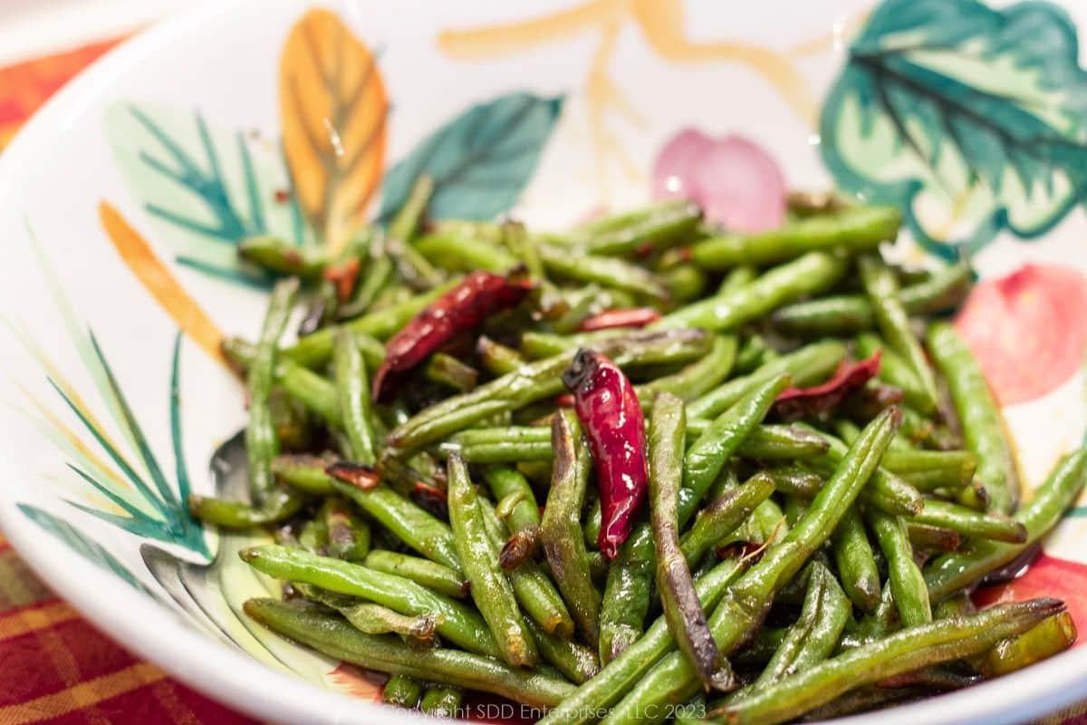 Sautéed green beans with red chili peppers in a serving bowl.